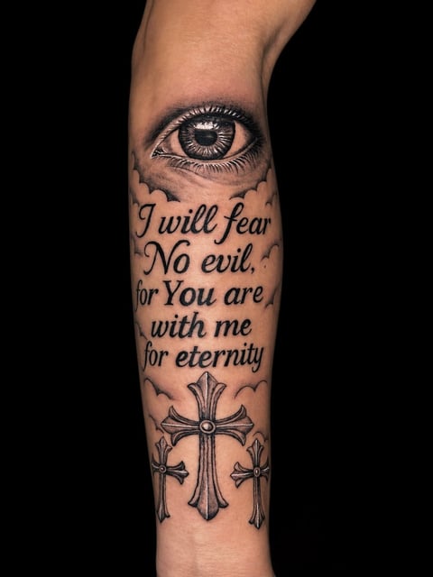 Forearm tattoo featuring an eye at the top, religious text reading I will fear No evil, for You are with me for eternity, and ornate crosses at the bottom on skin