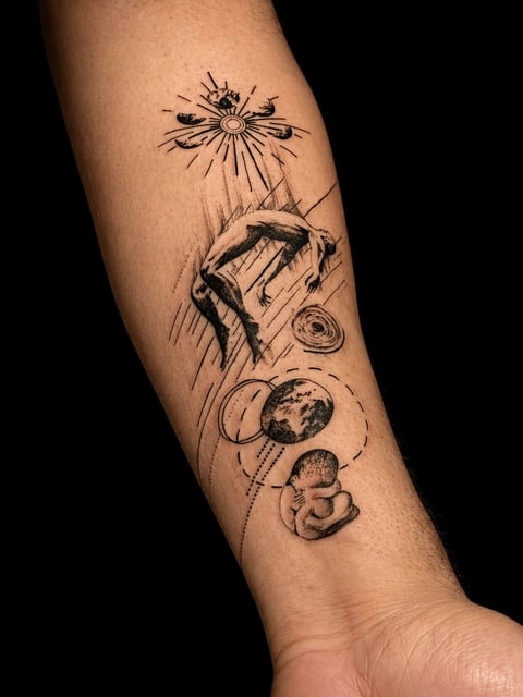 Black and white tattoo on an arm featuring a sun, human figure, moon phases, and planetary bodies in a vertical composition
